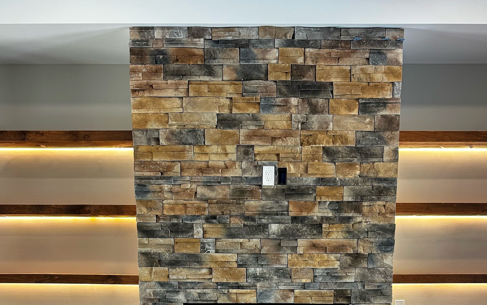 Stacked stone fireplace surround with warm lit floating shelves
