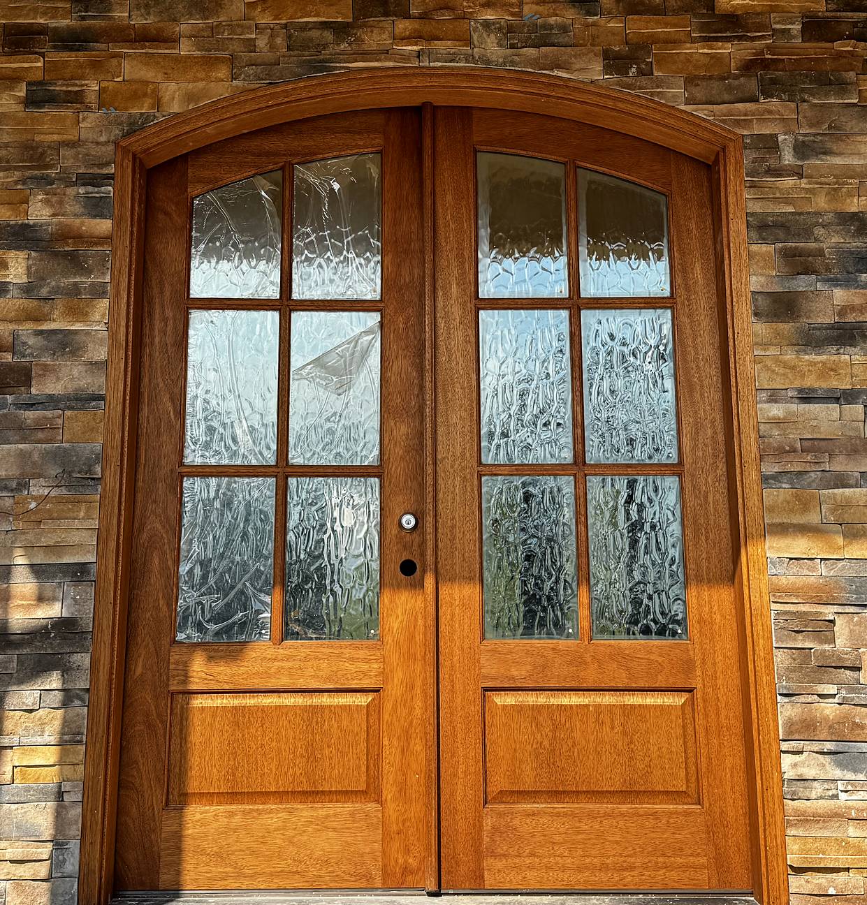 Stone veneer entry around an arched double door