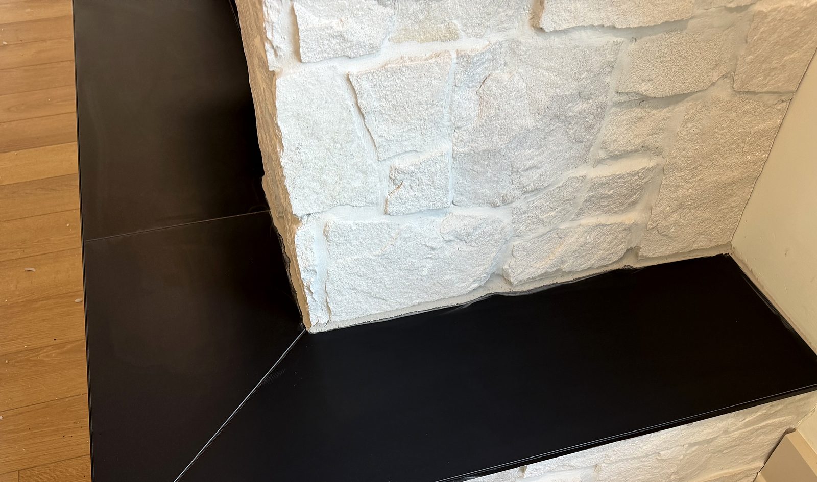 Close-up of a black mitered hearth and white stone