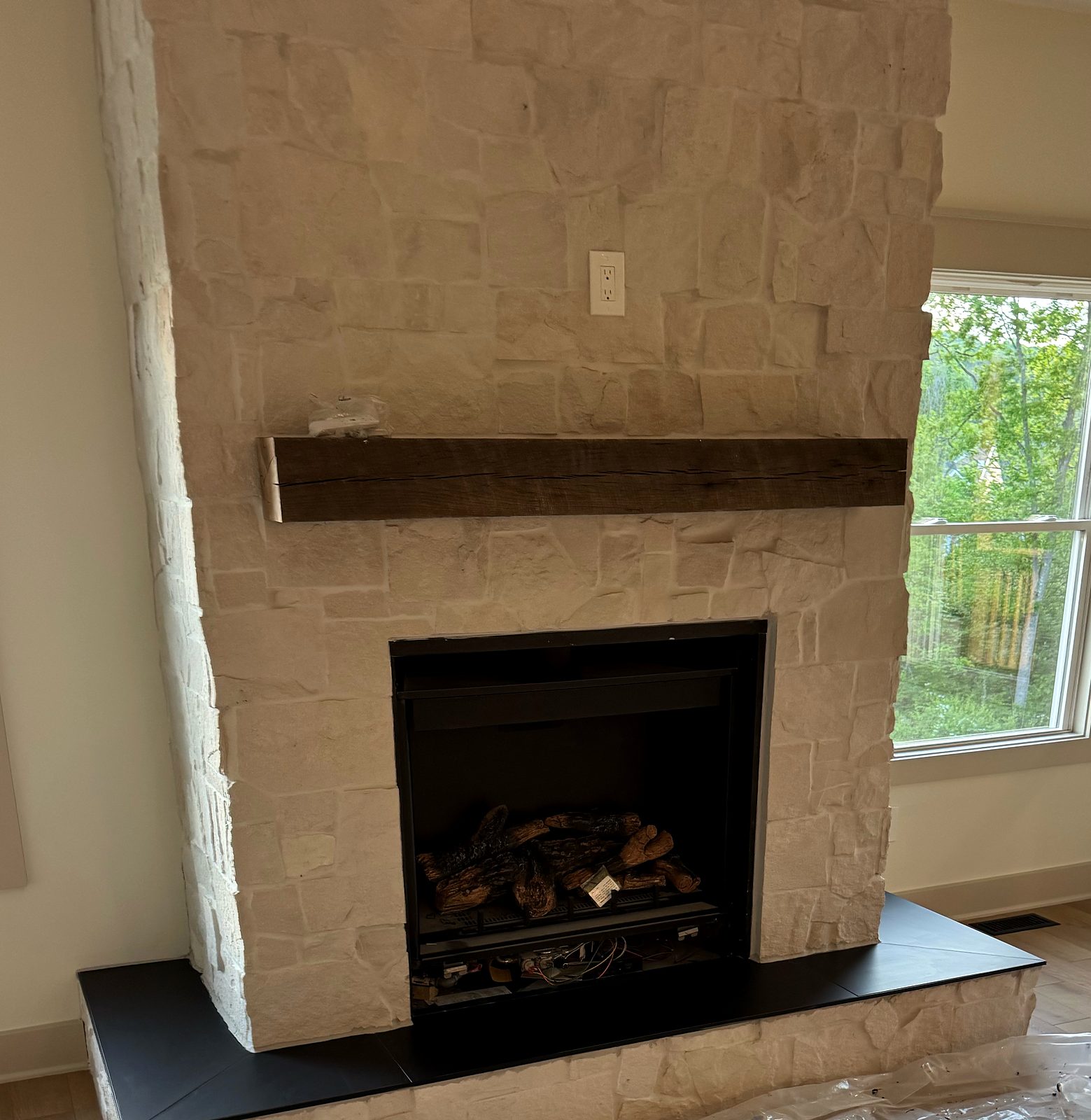 White stone fireplace with wood mantel and black hearth